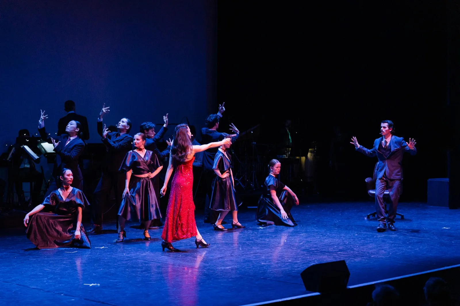 Danseuse en robe rouge au centre de la troupe en bleu